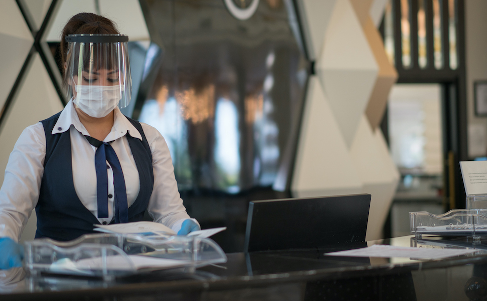 Receptionist lady welcomes her customer with protective face mask
